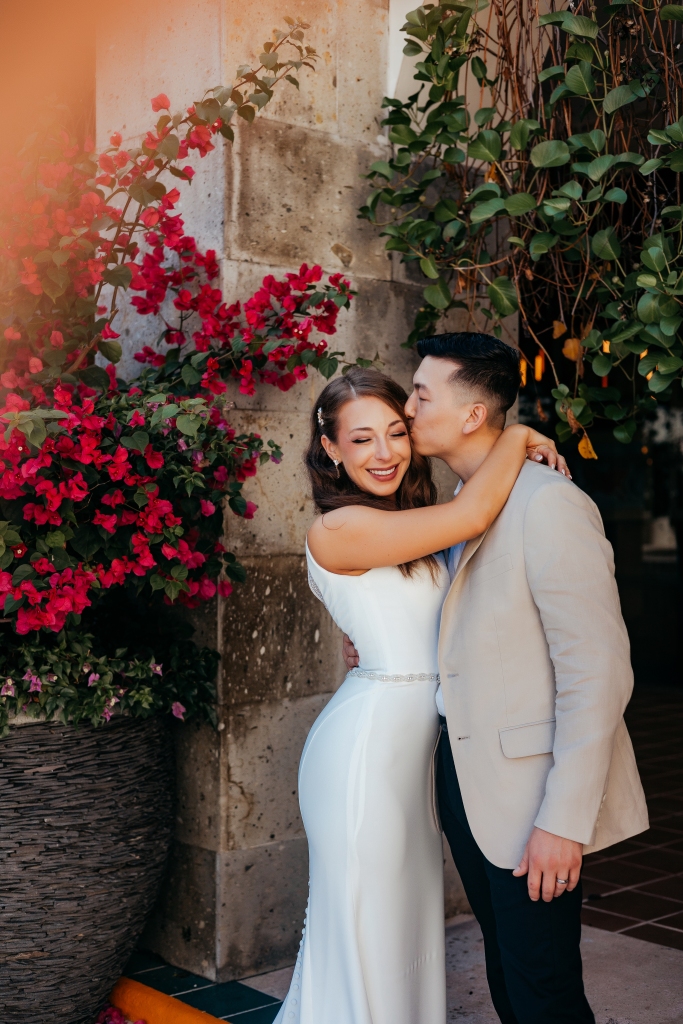 bride and groom kissing by flowers in Mexico